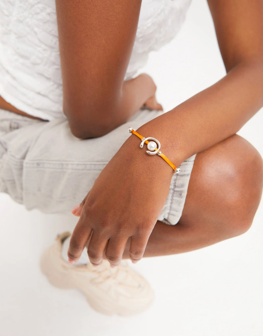UNO DE 50 - Pulsera de hilo naranja con perla shell fornitura bañada en plata de ley.