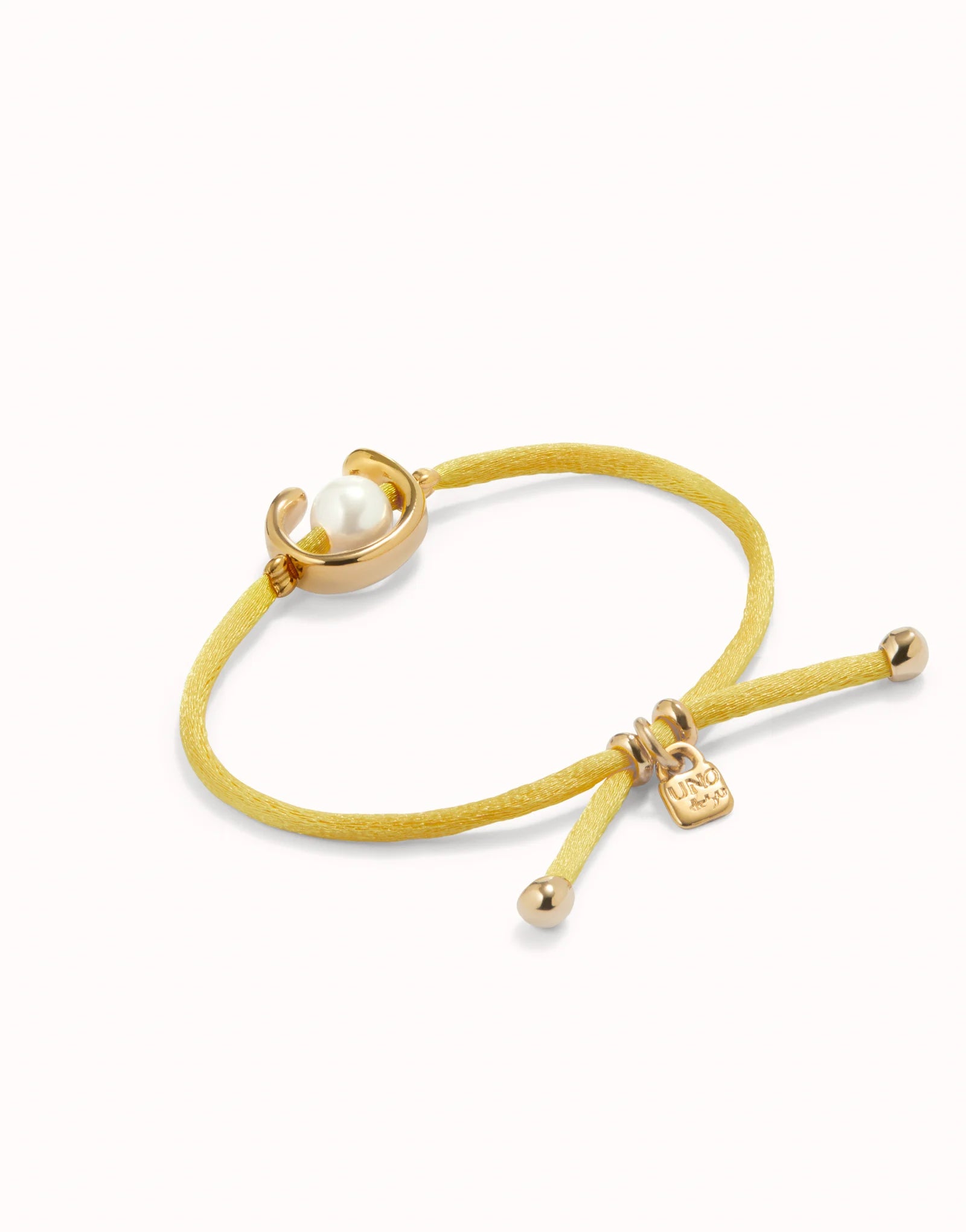 UNO DE 50 - Pulsera de hilo amarillo con perla shell fornitura bañada en oro 18k.